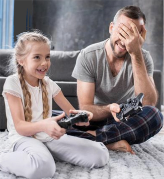 une fille qui rigole en jouant à la console avec un adulte